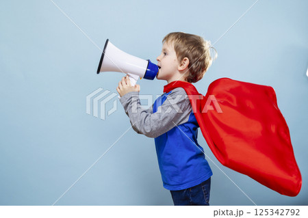 Boy wearing red cape shouting into megaphone 125342792