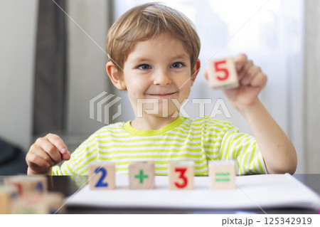 Smiling boy learning math with wooden blocks 125342919