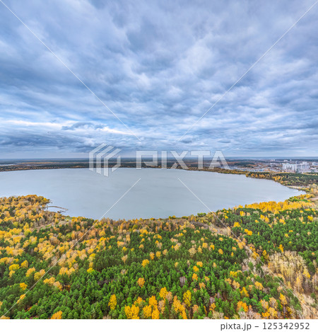 Autumn forest on lake shore at sunset and city on horizon, auerial view Autumn forest on lake shore at sunset and city on horizon, auerial view 125342952