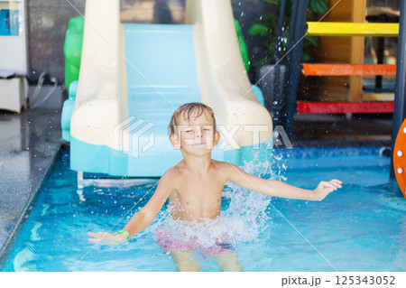 Boy splashing in pool from water slide 125343052