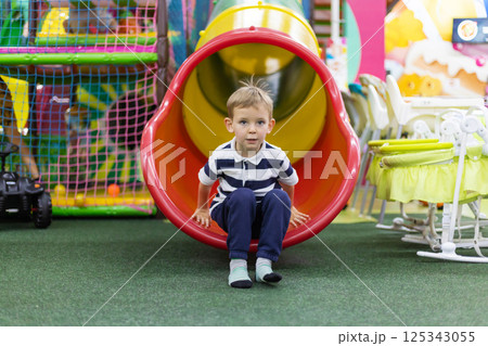 Boy sliding out of indoor tube slide Boy sliding out of indoor tube slide 125343055