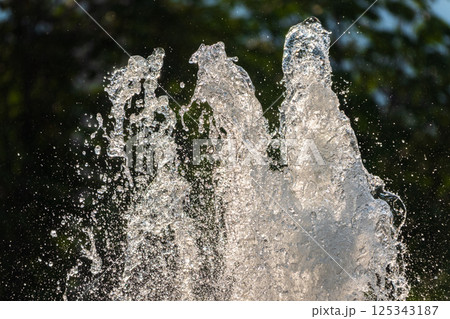 Splashes of water on dark background. Water sprays in sunny day close-up. Splashes of water on dark background. Water sprays in sunny day close-up. 125343187