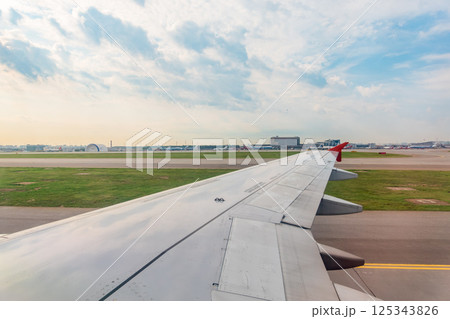 View of airplane wing, blue skies and green land during landing. Airplane window view. 125343826