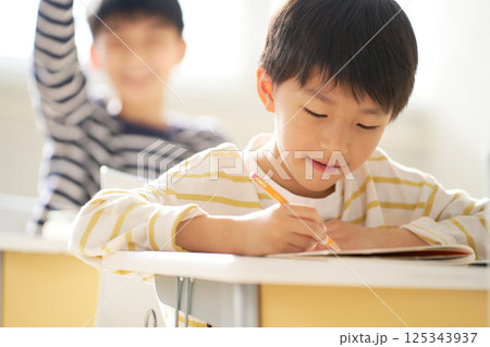 教室でノートに書き込む小学生 125343937