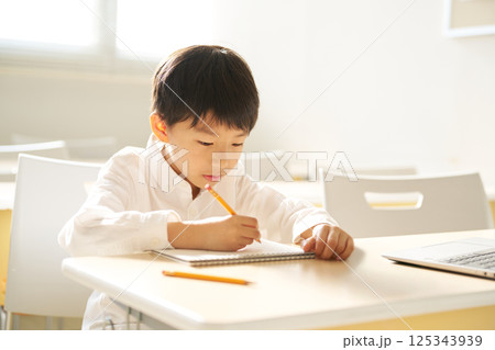 明るい教室で学習に取り組む小学生の男の子 125343939