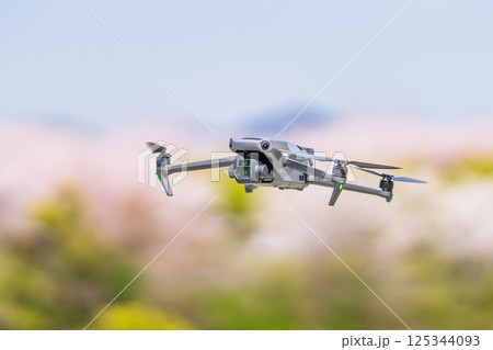 【春】桜を背景に飛行するドローン 125344093