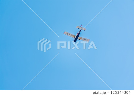 Small ultralight airplane with overhead wing and single propeller flying in sunset sky. 125344304