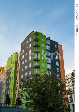 Modern multi-colored apartment building under a bright sky during late afternoon light in an urban neighborhood Modern multi-colored apartment building under a bright sky during late afternoon light in an urban neighborhood 125345034