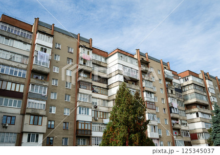 Urban block of residential buildings showcasing everyday life with balconies and hanging laundry under a bright sky Urban block of residential buildings showcasing everyday life with balconies and hanging laundry under a bright sky 125345037