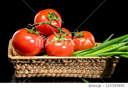 Fresh Tomatoes in Basket with Green Onions on Black Background Fresh Tomatoes in Basket with Green Onions on Black Background 125345691
