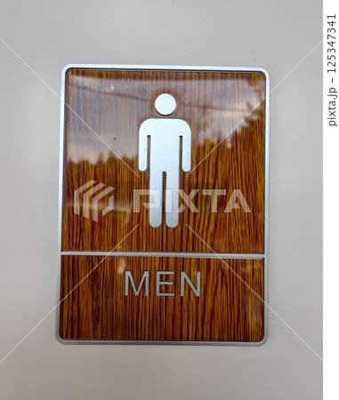 men restroom sign featuring simple design with wood grain background and silver icon in public space men restroom sign featuring simple design with wood grain background and silver icon in public space 125347341