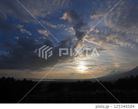 初夏の夕暮れ時、オレンジ色に光る夕日で虹色の彩雲が現れた。青空に印象的で綺麗だ。 125348584