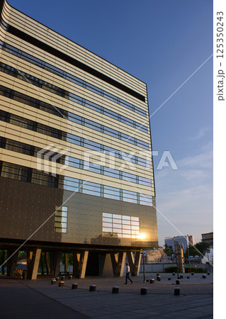 Glass office building reflecting golden sunlight at sunset Glass office building reflecting golden sunlight at sunset 125350243