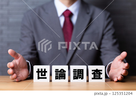 世論調査のブロックとスーツを着たミドル男性ビジネスマン 世論調査のブロックとスーツを着たミドル男性ビジネスマン 125351204