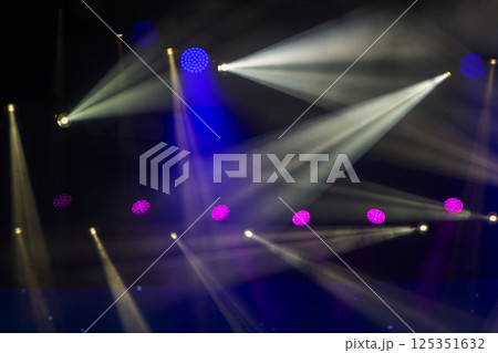 Stage white beams of light on dark blue background. Stage lighting for a concert. Stage white beams of light on dark blue background. Stage lighting for a concert. 125351632
