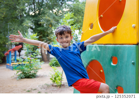 Happy child playing and climbing on colorful playground structure Happy child playing and climbing on colorful playground structure 125352071