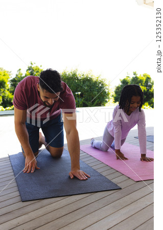 Father and daughter practicing yoga on mats outdoors, enjoying quality time together 125352130