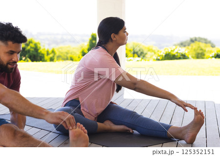 Family enjoying outdoor yoga session on deck, stretching and relaxing together 125352151