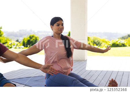 Woman practicing yoga outdoors, stretching arms on mat, enjoying peaceful nature Woman practicing yoga outdoors, stretching arms on mat, enjoying peaceful nature 125352168