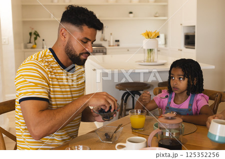 Father and daughter enjoying breakfast together at home, sharing quality time 125352256