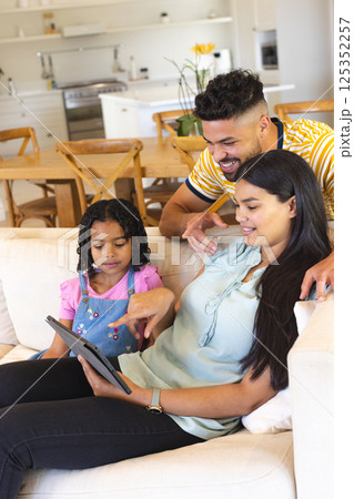 Family enjoying quality time together at home, using tablet on cozy sofa 125352257