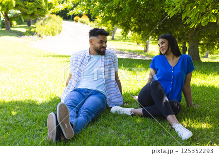 Couple relaxing on grass in park, enjoying sunny day and each other's company 125352293