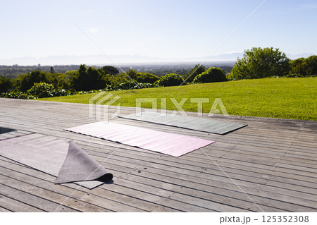 Yoga mats on wooden deck overlooking scenic landscape, ready for outdoor exercise, copy space Yoga mats on wooden deck overlooking scenic landscape, ready for outdoor exercise, copy space 125352308