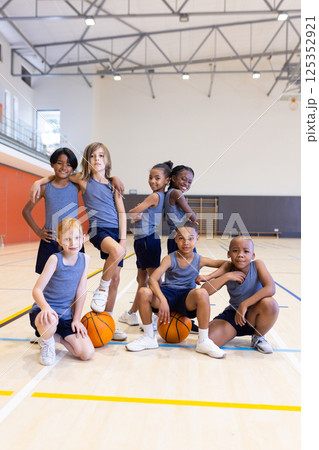 In school gym, group of diverse children posing with basketballs, smiling confidently In school gym, group of diverse children posing with basketballs, smiling confidently 125352921