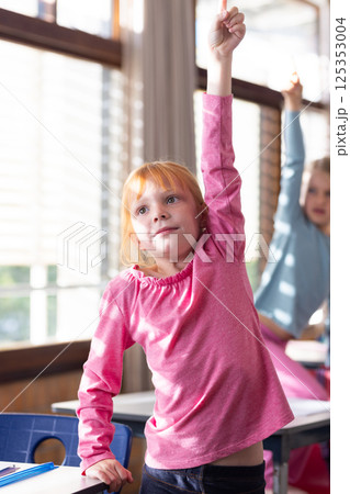 In school, girl raising hand in classroom, eager to answer question 125353004