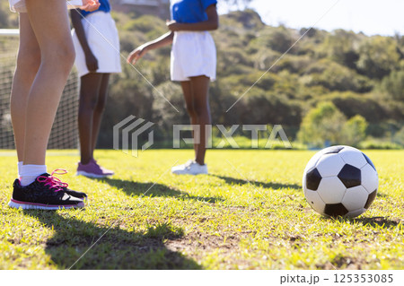 Playing soccer on school field, diverse girls in sports uniforms preparing for game 125353085