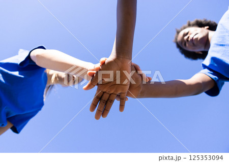 Holding hands, diverse girls in blue shirts forming unity at school event Holding hands, diverse girls in blue shirts forming unity at school event 125353094