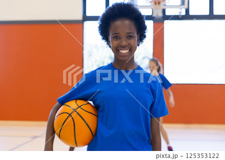 In school gym, african american girl holding basketball, smiling and ready to play In school gym, african american girl holding basketball, smiling and ready to play 125353122