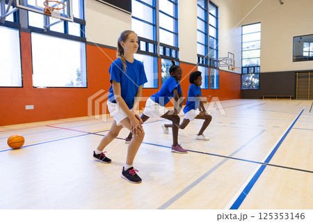 Exercising in school gym, diverse girls doing lunges during physical education class 125353146