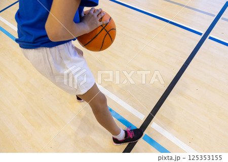 Playing basketball in school gym, girl dribbling ball on court 125353155