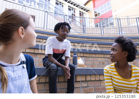 In school, three diverse kids sitting on steps, talking and enjoying break time In school, three diverse kids sitting on steps, talking and enjoying break time 125353180