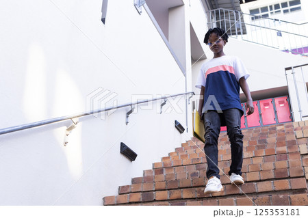 Walking down stairs, african american boy in casual clothes at school, looking confident 125353181
