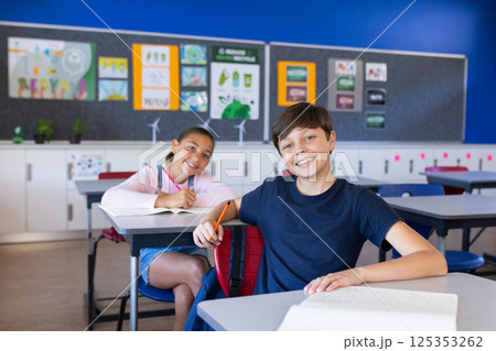 In school, students sitting at desks and smiling in classroom 125353262