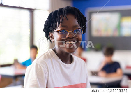 Wearing glasses, smiling boy enjoying school environment in classroom 125353321