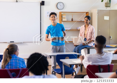 Presenting project in school, boy holding tablet while Indian female teacher and students watching Presenting project in school, boy holding tablet while Indian female teacher and students watching 125353333
