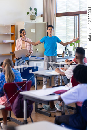 Presenting in classroom, boy engaging indian female teacher and students watching in school 125353334