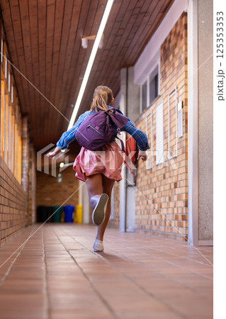 Running in school hallway, girl with backpack excitedly heading to class 125353353