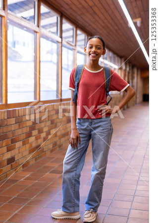 Smiling student with backpack standing in school hallway, posing confidently Smiling student with backpack standing in school hallway, posing confidently 125353368