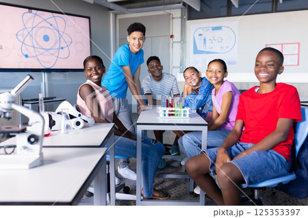 In school science lab, group of students smiling and sitting around table 125353397