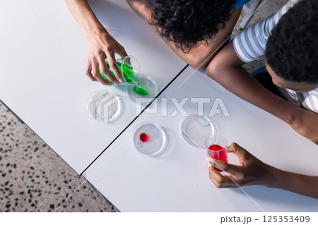 Conducting science experiment with colorful liquids and petri dishes, students in school Conducting science experiment with colorful liquids and petri dishes, students in school 125353409