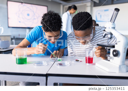Conducting science experiment with beakers and microscope, students in school classroom 125353411