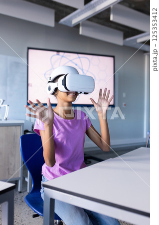 Using VR headset, student in school classroom experiencing virtual reality Using VR headset, student in school classroom experiencing virtual reality 125353412