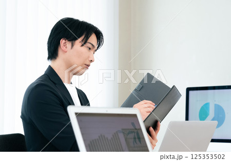 書類をチェックするカジュアルスタイルのビジネスマン 125353502