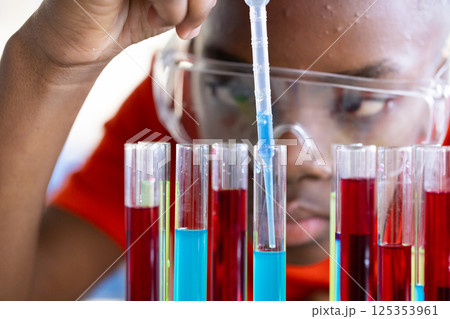In school, child conducting science experiment with test tubes and pipette In school, child conducting science experiment with test tubes and pipette 125353961