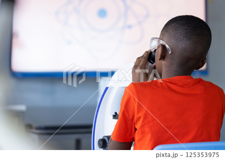In school, boy using microscope for science experiment in classroom, copy space In school, boy using microscope for science experiment in classroom, copy space 125353975