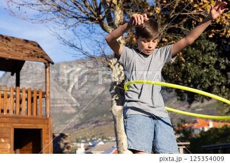 Playing with hula hoop, boy enjoying outdoor activity at school playground 125354009